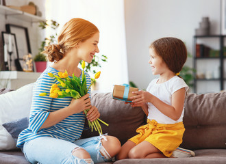 Wall Mural - happy mother's day! child daughter   gives mother a bouquet of flowers to tulip and gift.