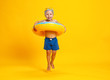 © JenkoAtaman - happy child boy in swimsuit with swimming ring donut on colored yellow background