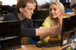 © Nestor - Two students, wearing in casual clothes, discussing joint project in classroom at university. Young handsome boy pointing on computer screen and his beautiful female classmate looking at him.