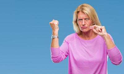 Canvas Print - Middle age blonde woman eatin pink macaron biscuit over isolated background annoyed and frustrated shouting with anger, crazy and yelling with raised hand, anger concept