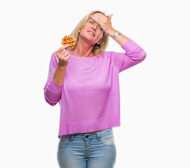 Wall Mural - Middle age blonde woman eating sweet waffle over isolated background stressed with hand on head, shocked with shame and surprise face, angry and frustrated. Fear and upset for mistake.