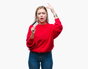 Poster - Young blonde woman holding credit card over isolated background annoyed and frustrated shouting with anger, crazy and yelling with raised hand, anger concept