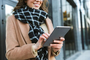 Wall Mural - Woman outdoors walking by street using tablet computer.