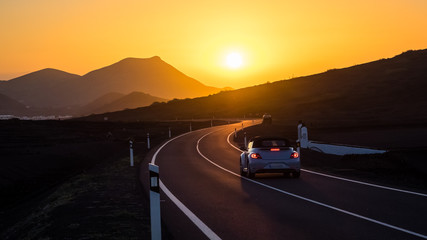 Car on a winding road driving towards sunset