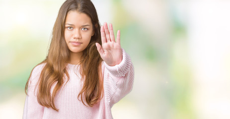 Sticker - Young beautiful brunette woman wearing pink winter sweater over isolated background doing stop sing with palm of the hand. Warning expression with negative and serious gesture on the face.