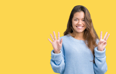 Canvas Print - Young beautiful brunette woman wearing blue winter sweater over isolated background showing and pointing up with fingers number eight while smiling confident and happy.