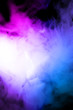 Male hand holds vape in thick vape fog or smoke. Vape clouds around hand with vape on black background. Fog is dual color — blue and purple. Stock isolated colorful smoke with spray glycerine.