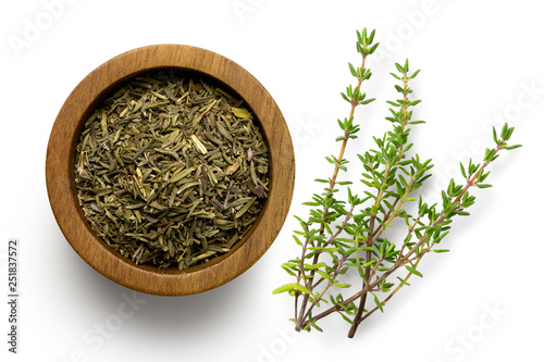 Fotomural Dried rubbed thyme in a dark wood bowl next to fresh thyme sprig isolated on white from above