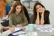 © Nestor - Beautiful girls carefully listening and writing at lectures in private school. Two students writing down information while other dreaming about something. Young pupils working on common project.