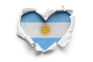 Heart shaped hole torn through paper, showing satin texture of flag of Argentina. Isolated on white background