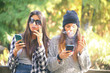 two girls smoking cigarettes and using smart phones. concept of addiction to smoking and smart phone dependency..