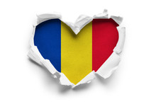 Heart Shaped Hole Torn Through Paper, Showing Satin Texture Of Flag Of Romania. Isolated On White Background