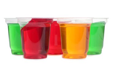 Jam in plastic cups with raw fruit on white background