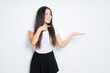 © Krakenimages.com - Beautiful brunette woman over isolated background amazed and smiling to the camera while presenting with hand and pointing with finger.