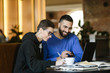 © proimagecontent - Male and female students discussing something together while drinking coffee at the cozy cafe