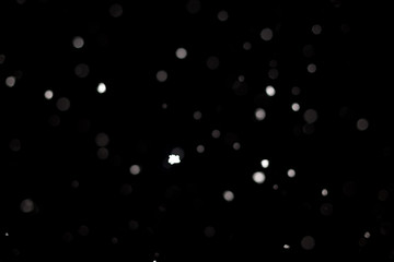 Wall Mural - Snowstorm texture. Bokeh lights on black background, shot of flying snowflakes in the air