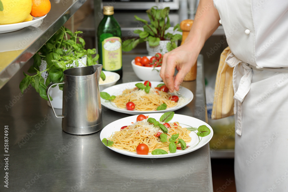 Kucharz przygotowuje spaghetti na białych talerzach. - obrazy, fototapety, plakaty 