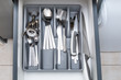 Opened drawer with shiny silver cutlery in modern kitchen. Close up.
