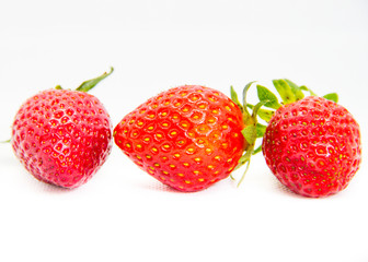 Several red strawberries with leaves on a white background