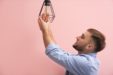 Wall Mural - Man changing light bulb in lamp on color background