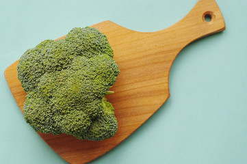 Top view of broccoli on the wooden cutting board. The blue background.