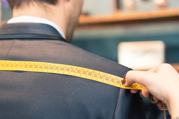 Detail of tailor's hands taking measurements for a man dress