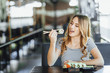 © Тарас Нагирняк - A young beautiful blond girl eating sushi on the summer terrace of a Japanese restaurant