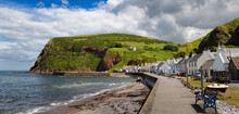 Row Of White Houses Of Pennan Coastal Fishing Village On North Sea In Aberdeenshire Scotland UK With Black Hill Sea Cliff