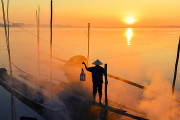 Asian fishermen hold fishing equipment on their boats to wait for fish in the Mekong River. In the morning of the new day