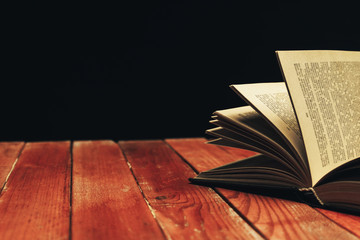 Aufkleber - One open old book on a red wooden table. Beautiful dark background.