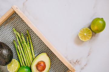 Fresh green healthy vegetables in wooden box on white marble background, top view