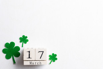 Wall Mural - Block calendar for St Patrick's Day, March 17, with green clover leaf, green water and paper tag on white wooden background