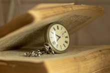 Old Pocket Watch And A Battered Book On The Table