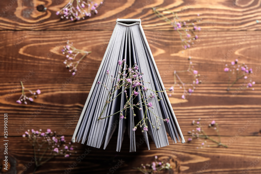 Book with flowers on wooden background