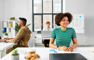 Poster - business and people concept - happy smiling african american woman with smart watch at office