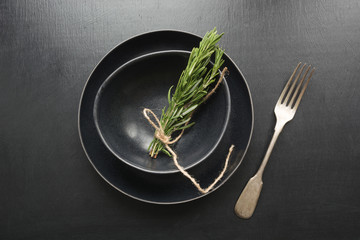 Wall Mural - Vintage table place setting with rosemary sprig on black. Top view. Concept. Minimalism