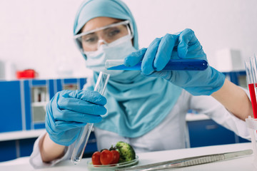 Wall Mural - female muslim scientist holding test tubes during experiment with vegetables in laboratory