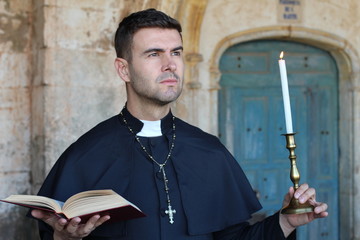 Religious man holding the Bible and a candle 