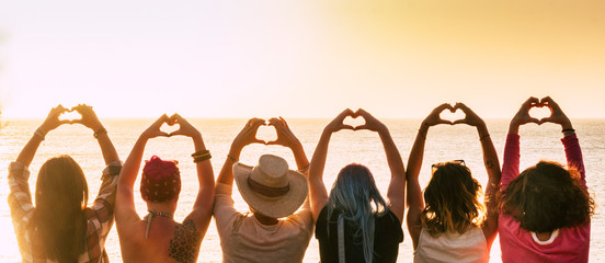group of diversity alternative young woman enjoying the sunset at the sea doing hearth symbol with h
