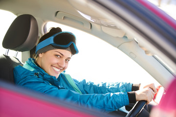 girl driving a car while preparing for skiing on a snowy mountain