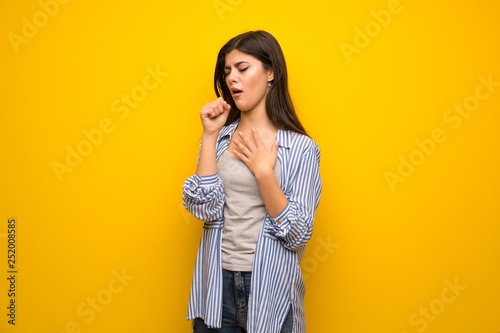 Teenager girl over yellow wall is suffering with cough and feeling bad Fotobehang