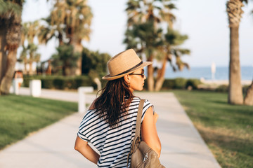 Wall Mural - Pretty pan asian tourist girl in hat and sunglasses walking outdoor.