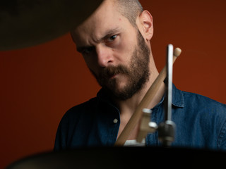 Boy playing drum with jeans shirt and dark background