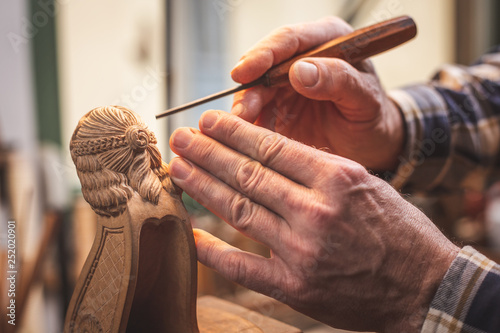 Fotografía Hände eines Mannes beim Schnitzen einer Holzfigur