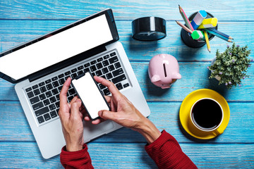 Wall Mural - flat lay, top view desk table.man using mobile phone at desk table with blank screen laptop computer