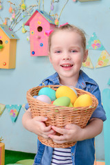 Cute smiling little girl with basket full of colorful easter eggs