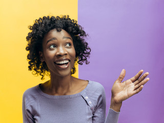 Happy woman standing and smiling isolated on trendy color studio background. Beautiful female half-length portrait. Young emotional afro woman. The human emotions, facial expression concept.