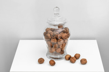 Glass jar with walnuts on table on a white background. Healthy tasty organic food concept