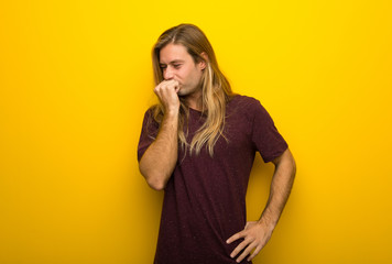 Wall Mural - Blond man with long hair over yellow wall having doubts