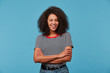 Young african american woman over blue wall wearing stripped t-shirt smiling with happy face winking at the camera standing with arms crossed